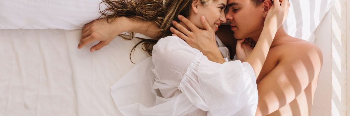 blij-koppel-knuffelend-in-bed-wit-shirt